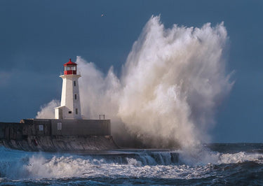 Coastal canvas art print of a lighthouse in a raging sea by Feeling at Home, showcasing a dramatic maritime scene.