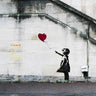 Street scene canvas art print featuring graffiti attributed to Banksy, created by Feeling at Home, showcasing vibrant urban street art.
