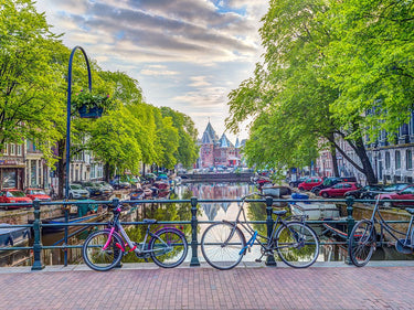 Amsterdam canal scene with parked bicycles, displayed as a Feeling at Home canvas art print by Flint Helen.