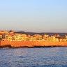 Coastal canvas art print of Alghero ramparts at sunset by Feeling at Home, featuring vibrant colors and scenic seaside views.