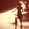 Woman shadow bike photography canvas art print by Feeling at Home, showcasing a silhouette of a woman riding a bike.
